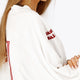 Woman wearing the Osaka women v-neck cropped sweater white with logo in red. Side view