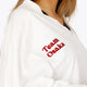 Osaka women v-neck cropped sweater white with logo in red. Front detail logo view