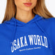 Woman wearing the Osaka women cropped hoodie inprincess blue with college logo in white. Front detail logo view