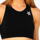 Woman wearing the Osaka women tech sports bra in black with logo in grey. Front detail view