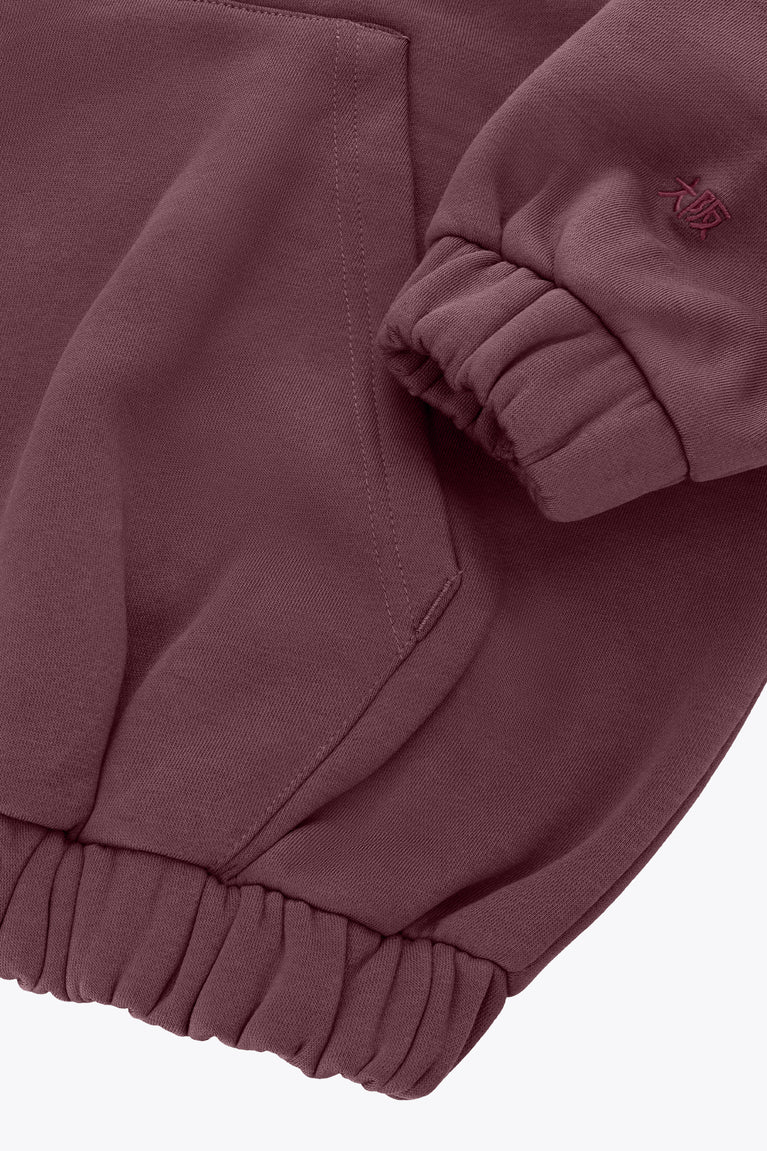 Plum sweater detail with ribbed cuff, side seam, and logo at sleeve