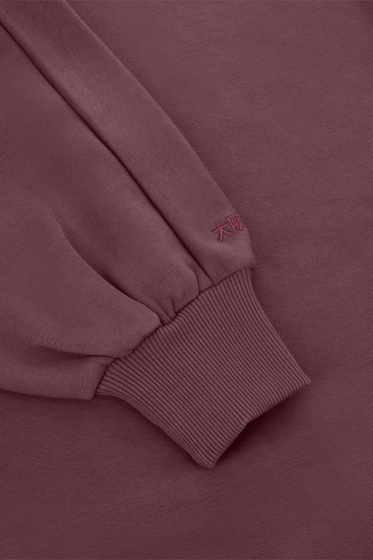 Women’s mockneck sweater close-up of ribbed sleeve cuff seam in dark plum