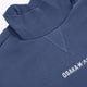 Blue mockneck sweater detail with ribbed collar and Osaka* logo embroidery