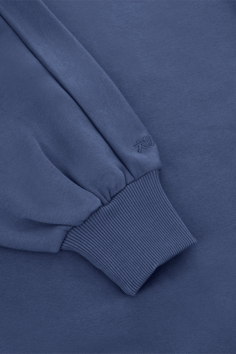 Blue sweater sleeve cuff with ribbed knit trim and small embroidered detail