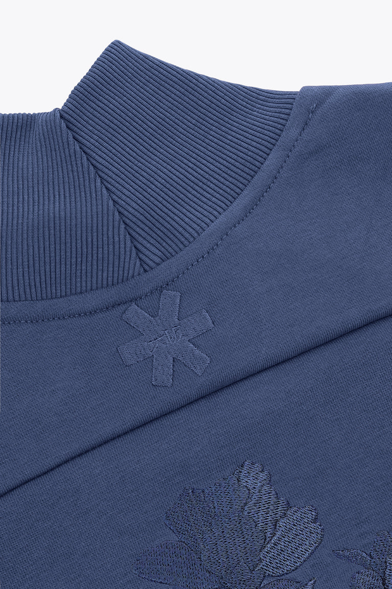 Blue mockneck sweater neckline with ribbed collar and cross-style embroidery