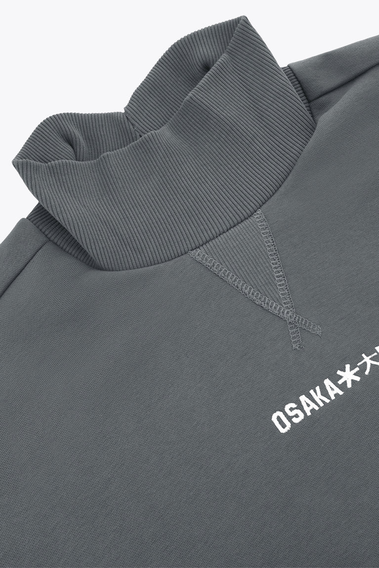Dark grey melange mockneck sweater with embroidered OSKA* detail and stitched collar seam.