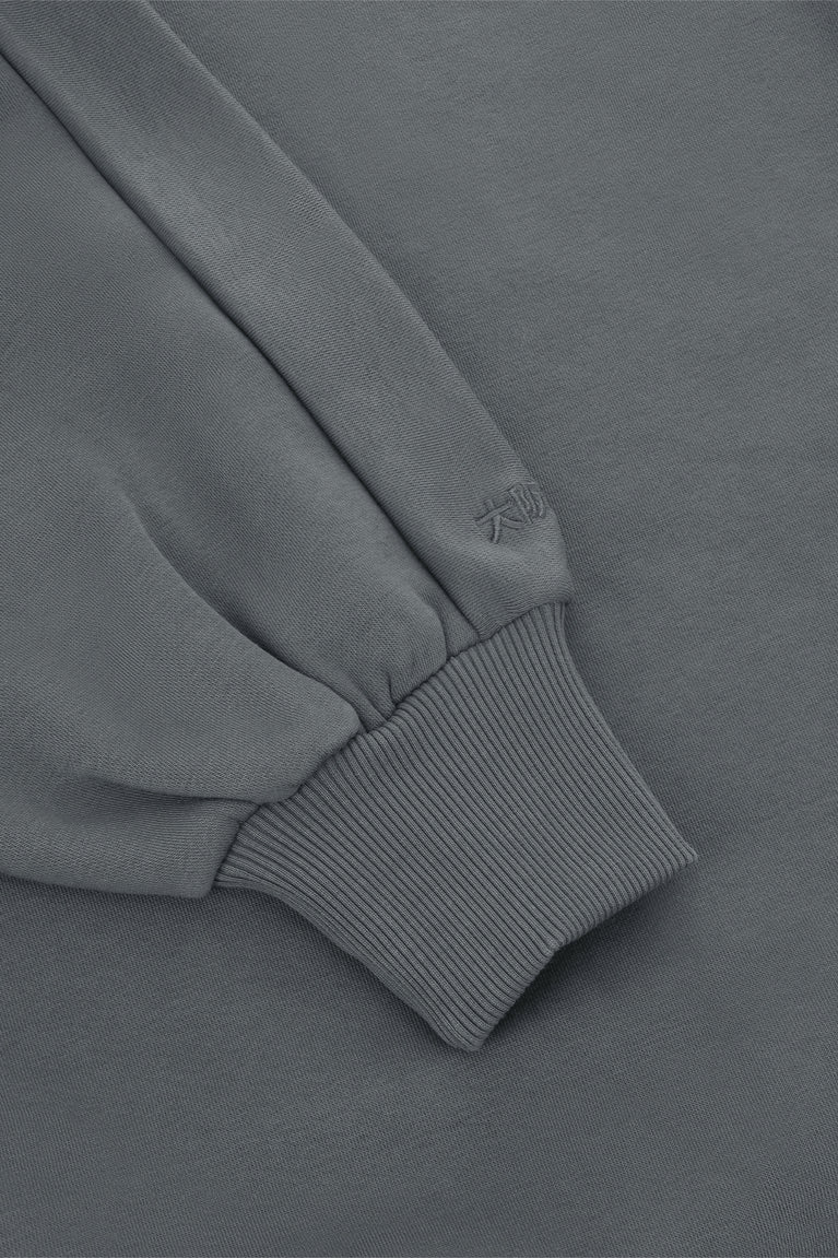 Dark grey melange sweater sleeve with ribbed cuff and stitched seam detail at cuff.