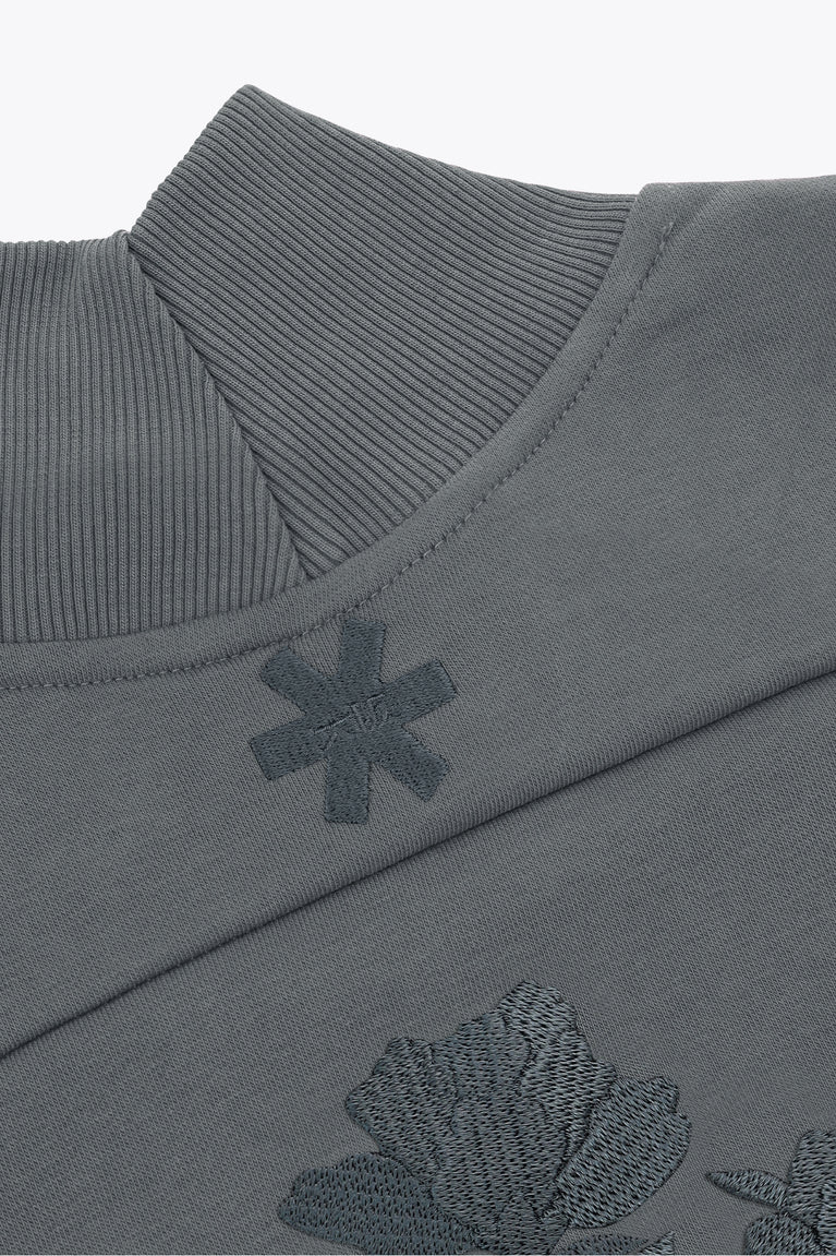 Dark grey melange mockneck sweater collar with ribbed trim and small embroidered cross.