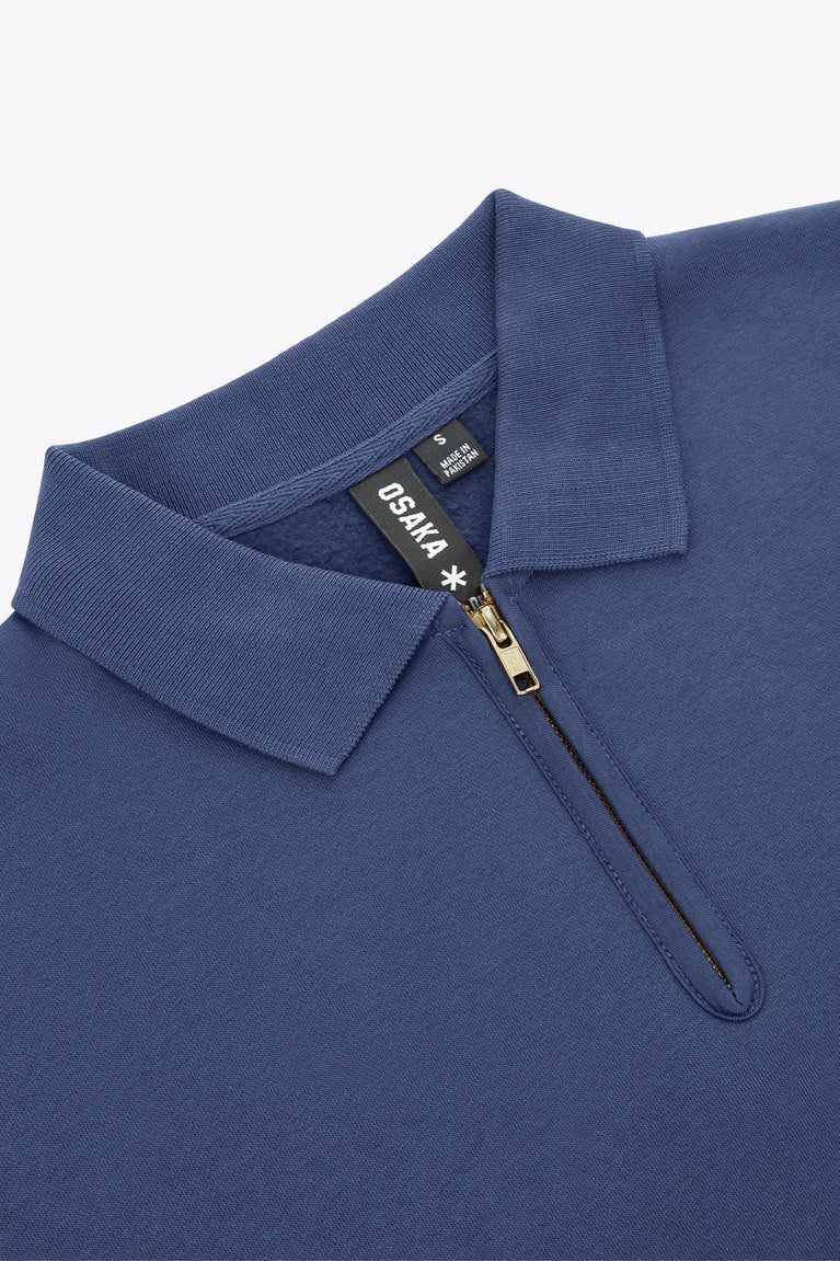 Blue women’s zip polo sweater close-up: flat collar and quarter-zip with gold pull