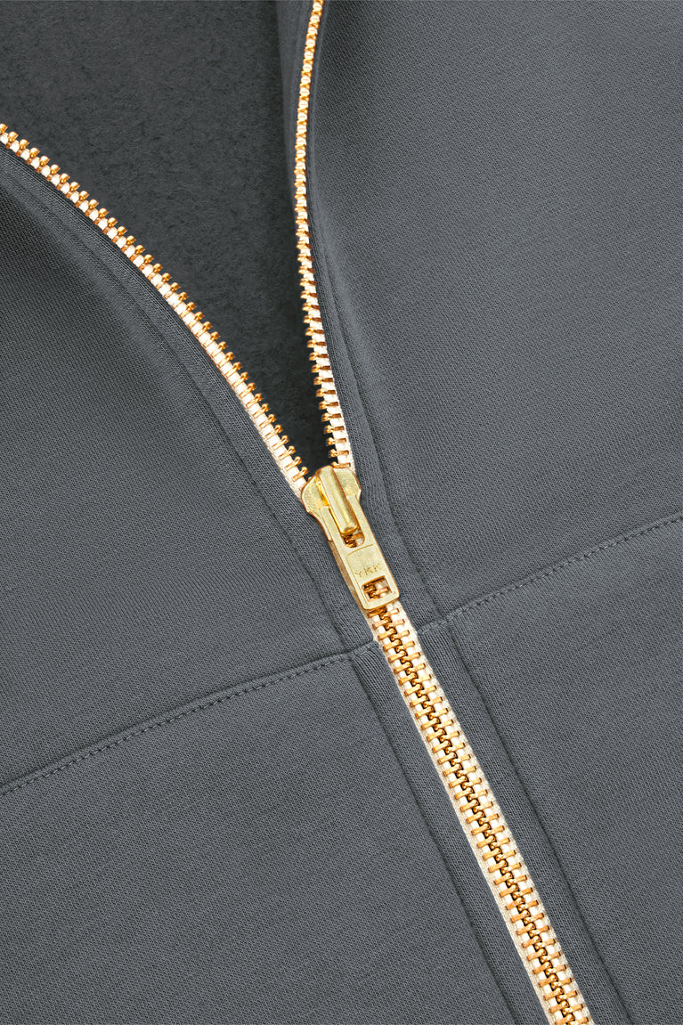 Full-zip hoodie zipper with gold-and-brown patterned tape and curved seam detail