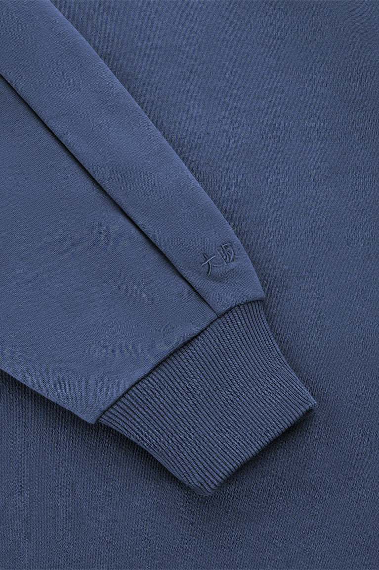 Men's navy half-zip sweater sleeve with ribbed cuff and small embroidered logo.