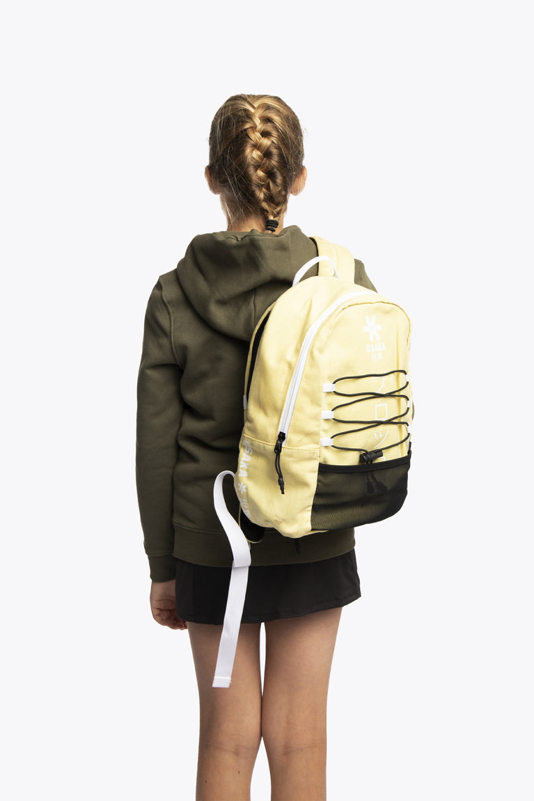 Osaka pro tour backpack in faded yellow with logo in white. Girl wearing the bag