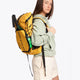  Pro Tour padel backpack in honey comb with logo in black. Woman wearing the bag, side view