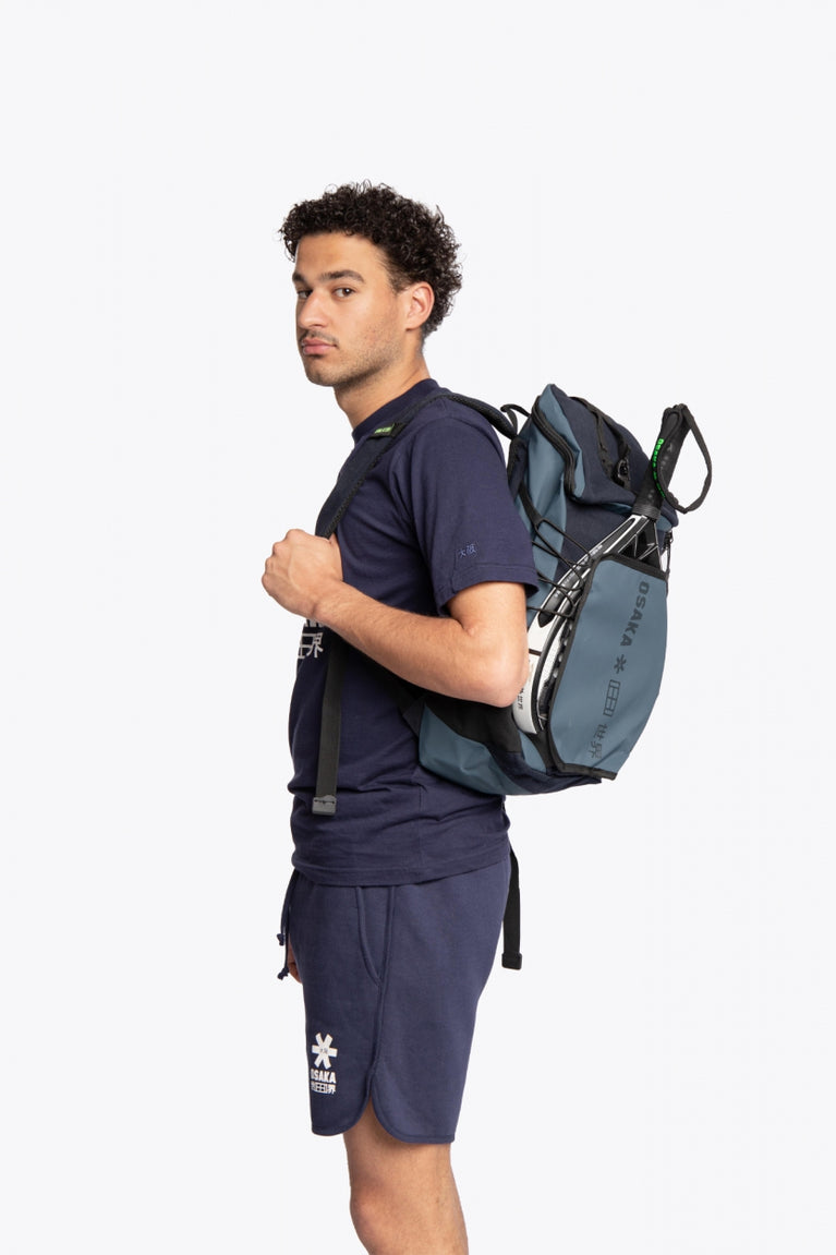  Pro Tour padel backpack in navy with logo in black. Man wearing the bag