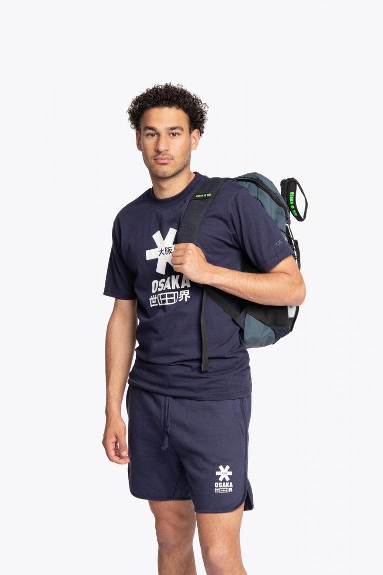  Pro Tour padel backpack in navy with logo in black. Man wearing the bag, front view