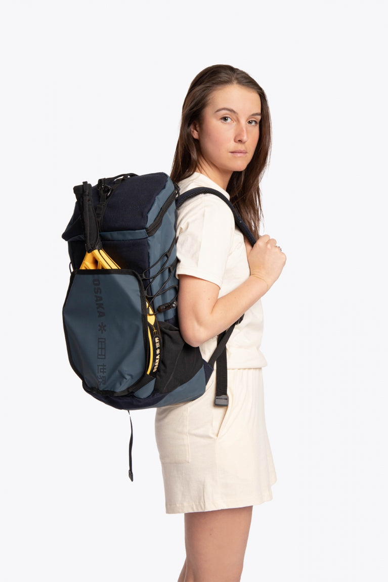  Pro Tour padel backpack in navy with logo in black. Woman wearing the bag