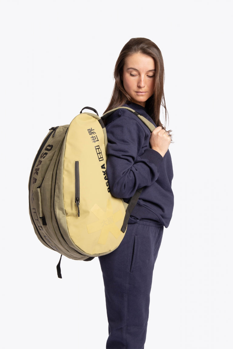 Pro Tour padel bag in olive with logo in black. Woman wearing the bag side view