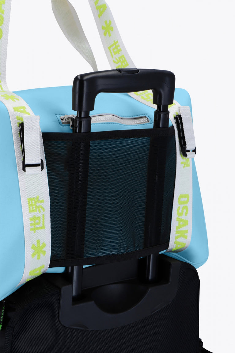 Osaka neoprene duffel bag in light blue with logo in white on the bag and in green on the straps. Detail back view