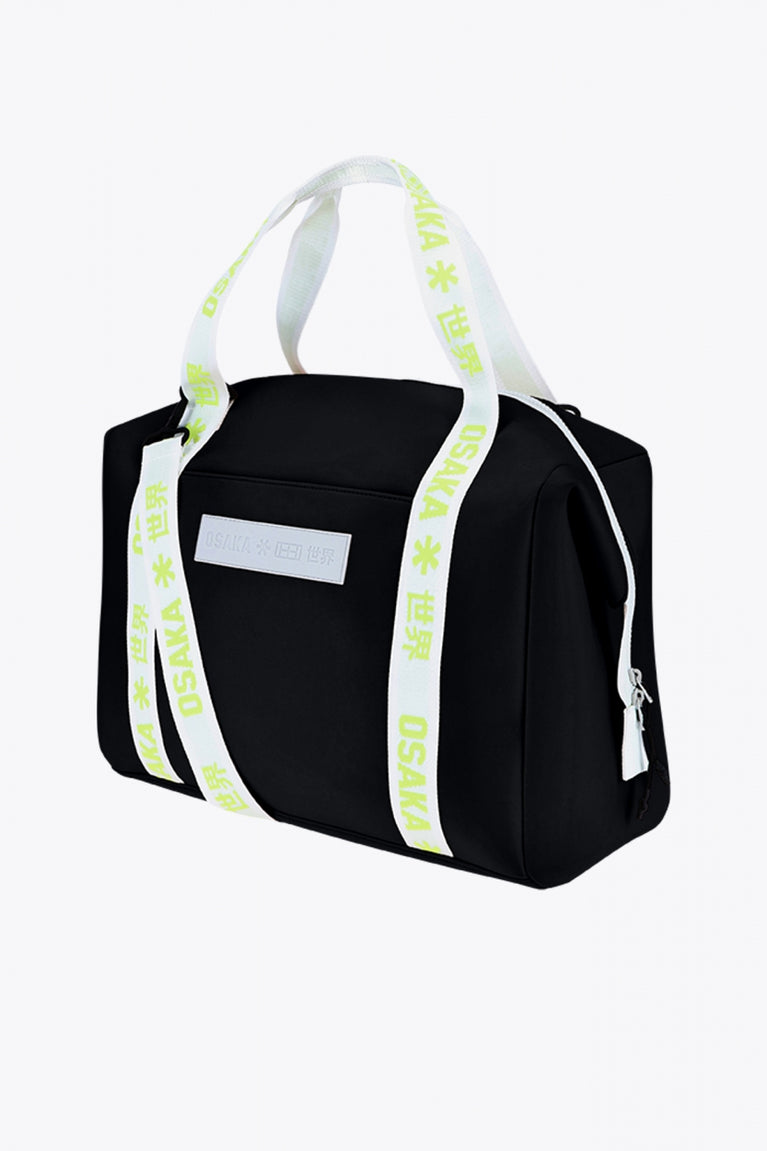 Osaka neoprene duffel bag in black with logo in white on the bag and in green on the straps. Side view
