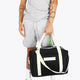 Osaka neoprene duffel bag in black with logo in white on the bag and in green on the straps. Man holding the bag