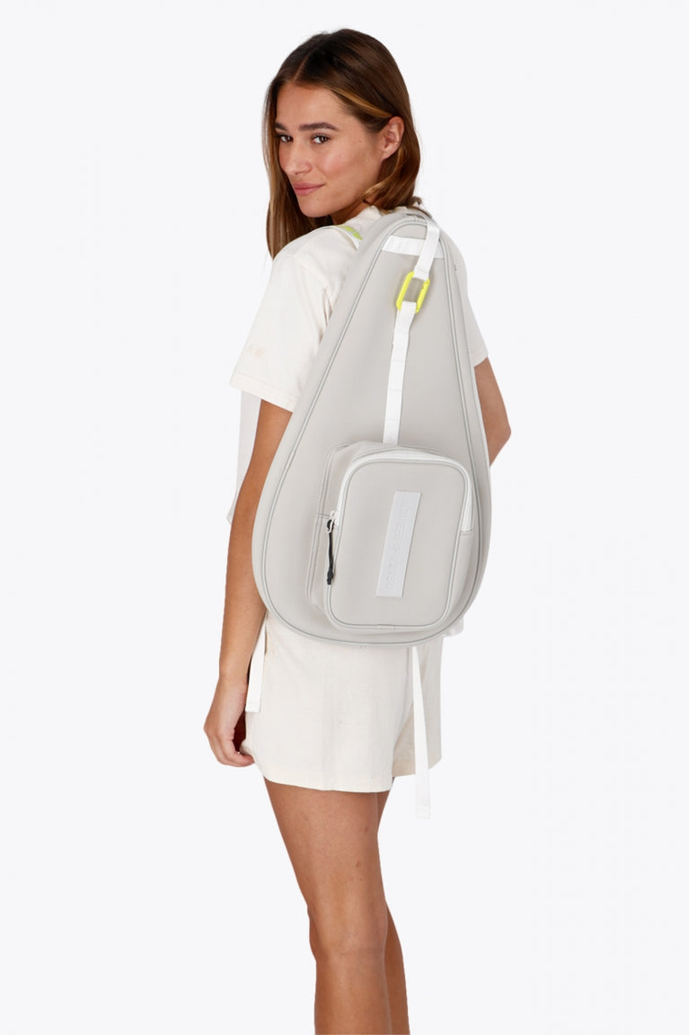 Osaka neoprene padel bag in light grey with logo in white. Woman wearing the bag
