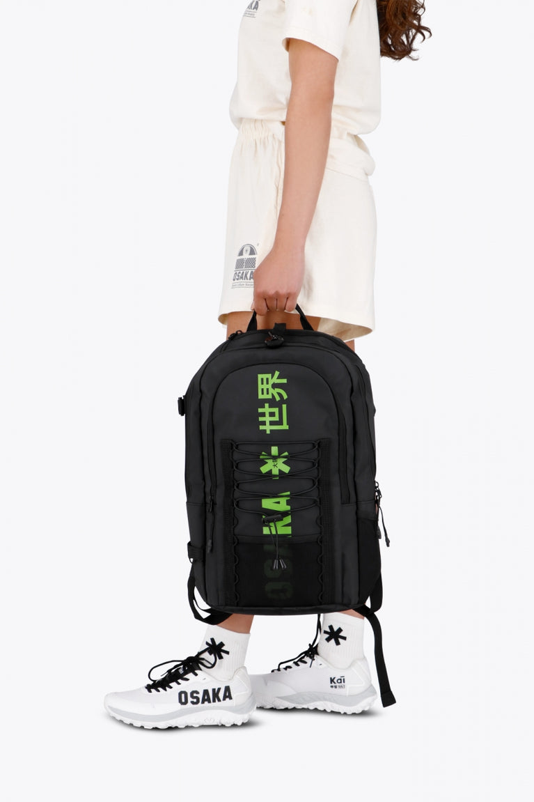 Osaka Pro Tour backpack in black with logo in green. Woman holding the bag