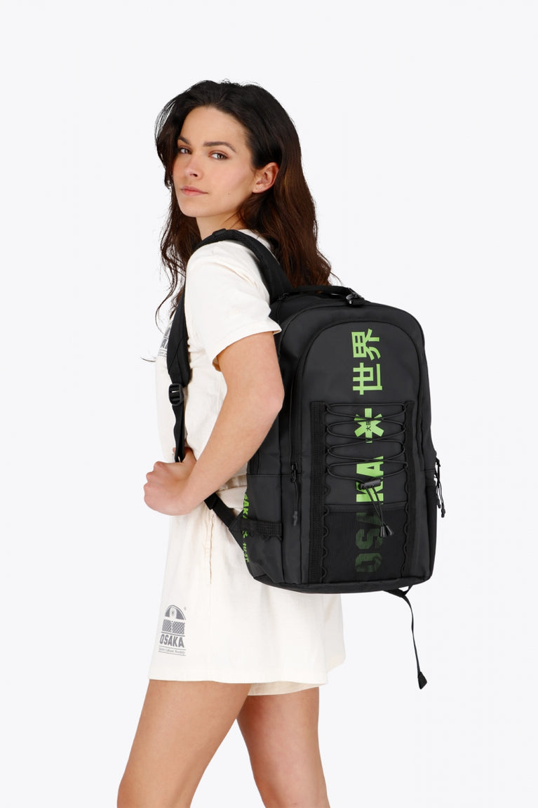 Osaka Pro Tour backpack in black with logo in green. Woman wearing the bag