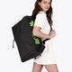 Osaka sports duffel bag in black with logo in green. Woman wearing the bag