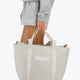 Osaka neoprene Tote bag in light grey with structure and logo in white. Woman holding the bag