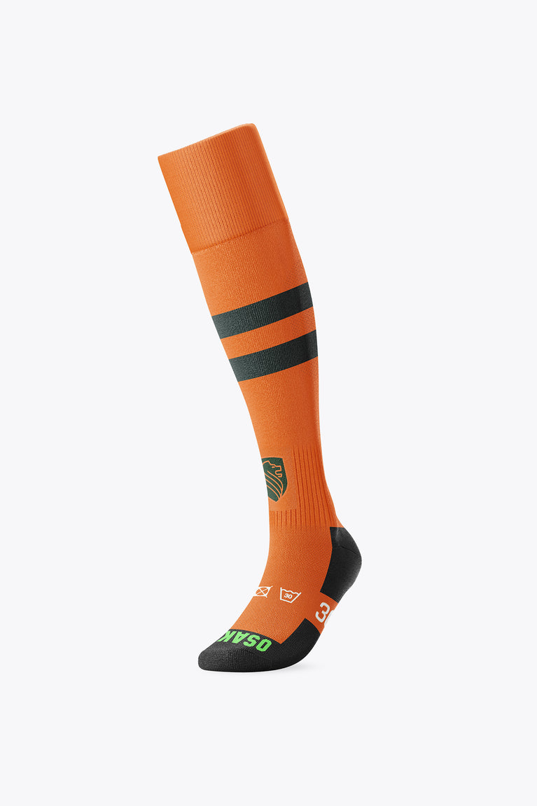Orange field hockey socks with black mid-calf stripe, black toe and heel, crest detail
