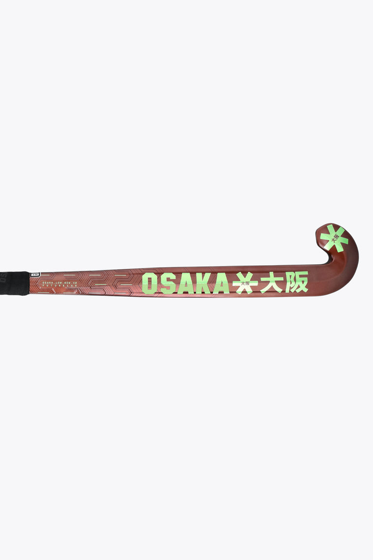 Brown field hockey stick with 'OSAKA' lettering and green star accents along blade.