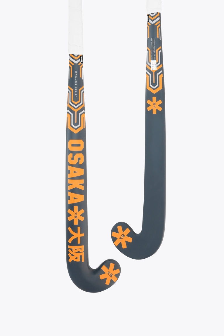 Field hockey stick head, dark gray with orange accent graphic on curved blade