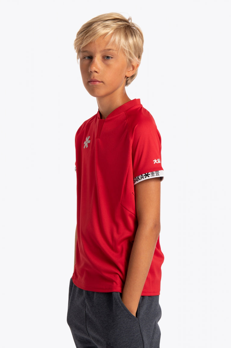 Boy wearing the Osaka Kids Jersey in Red. Side view