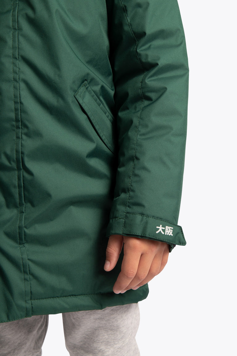 Boy wearing the Osaka Kids Stadium Jacket in Dark Green. Front detail sleeve view