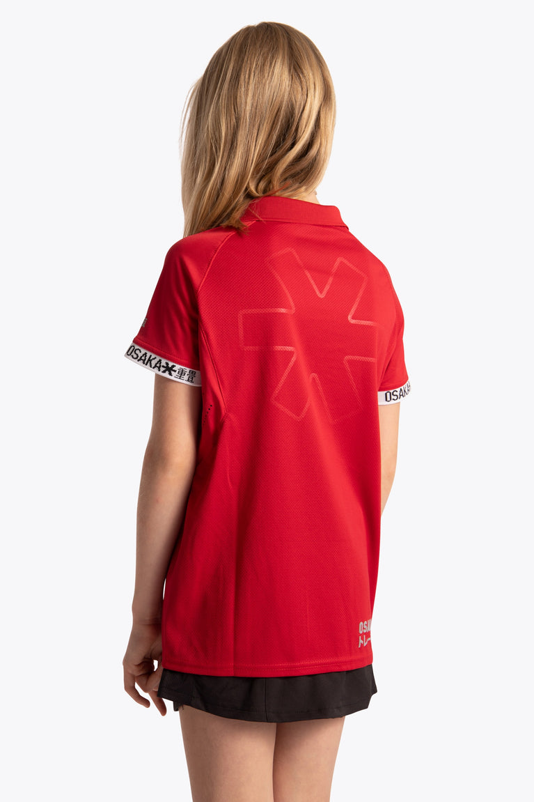 Girl wearing the Osaka Kids Polo Jersey in Red. Back view