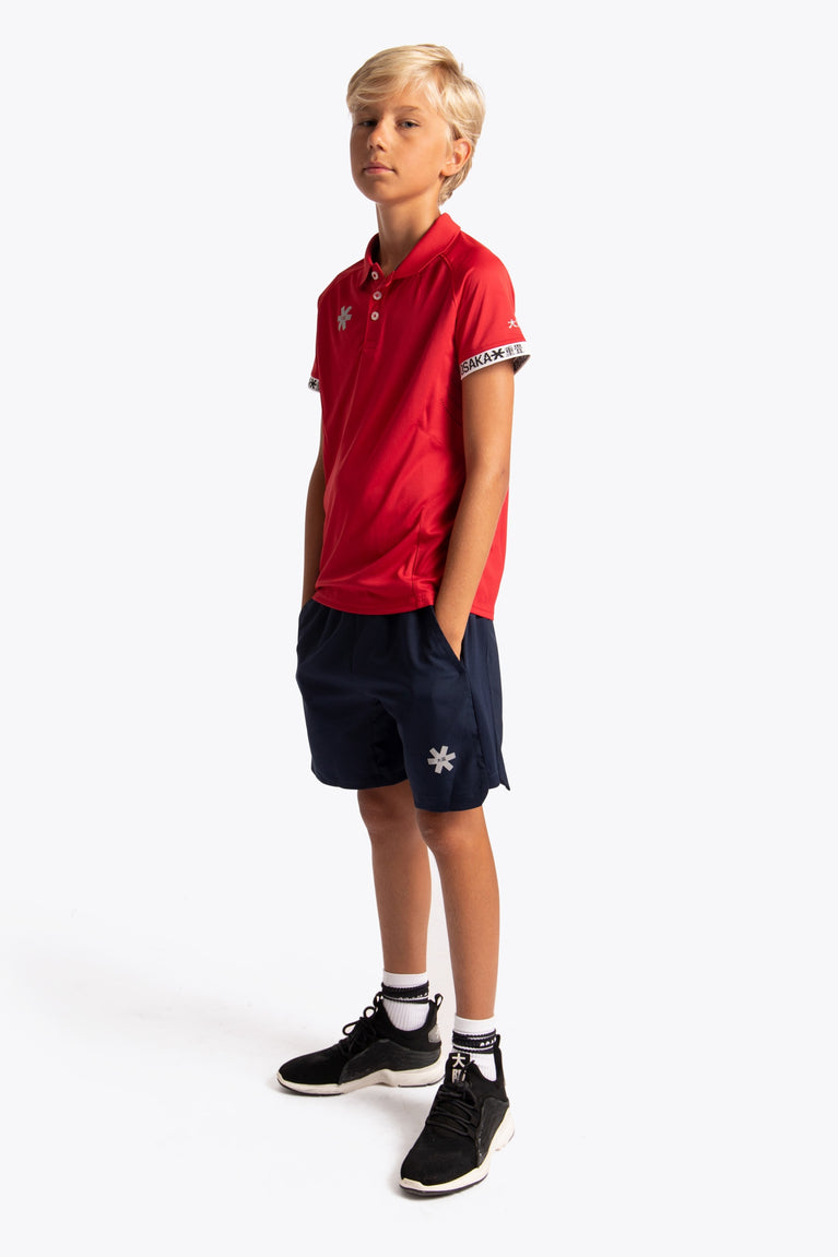 Boy wearing the Osaka Kids Polo Jersey in Red. Side view