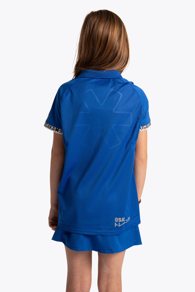 Girl wearing the Osaka Kids Polo Jersey in Royal blue. Back view
