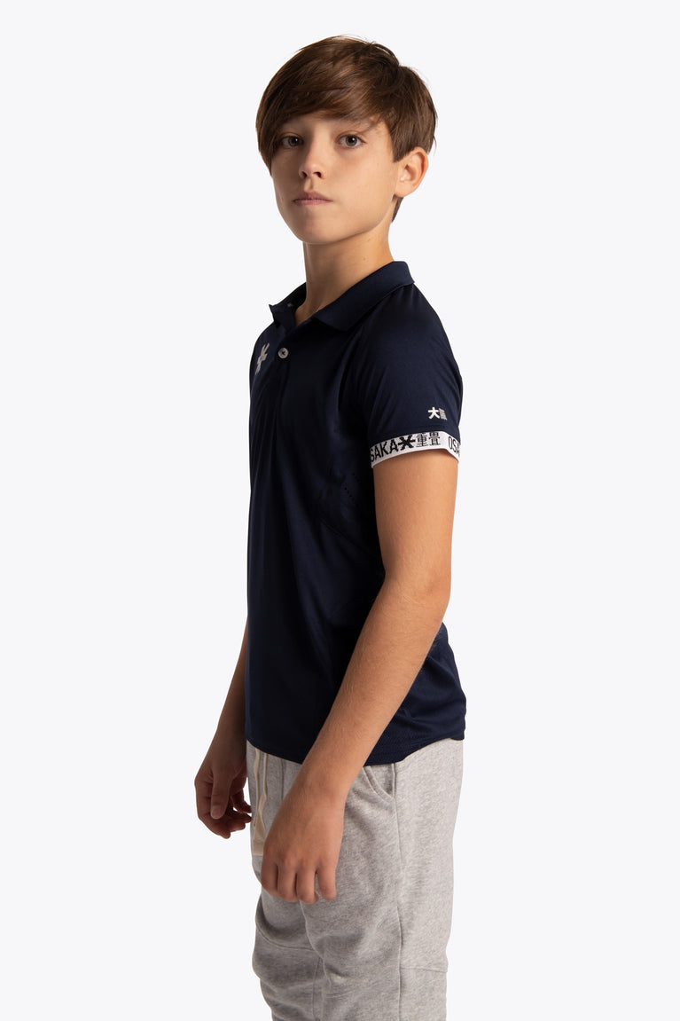 Boy wearing the Osaka Kids Polo Jersey in Navy. Side view