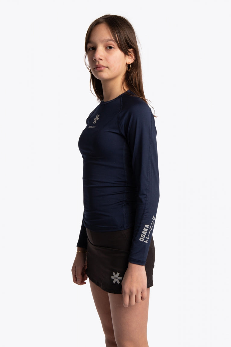 Girl wearing the Osaka Kids Baselayer Top in Navy. Side view