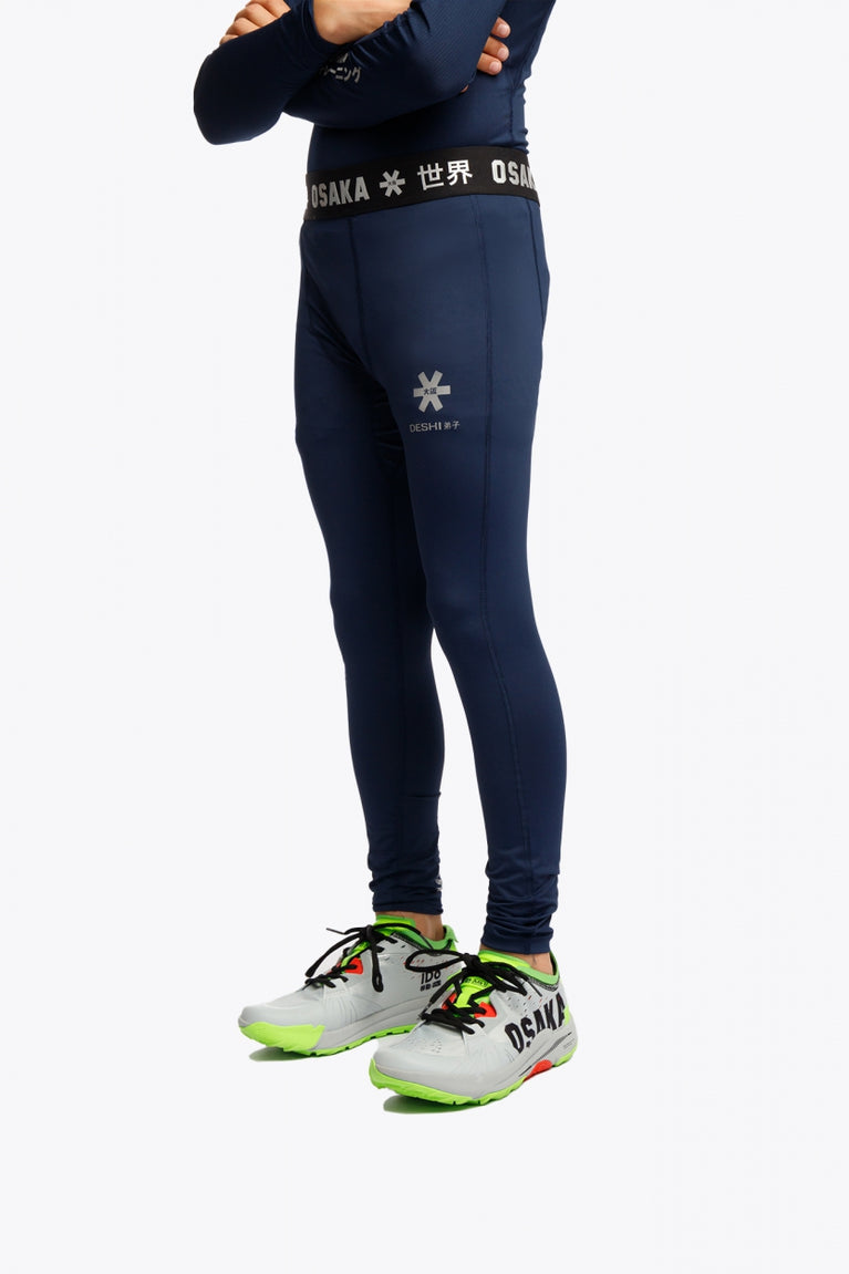 Model wearing the Osaka Kids Baselayer Tights in Navy. Side view