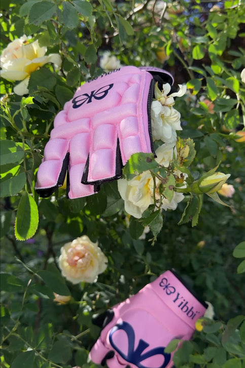 Pastel pink hockey glove with black palm and open fingers, padded wrist cuff
